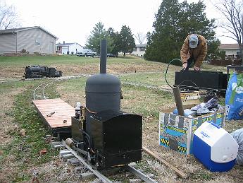 FirstSteamUpEver29Nov08 002 Saturday, 29-Nov-08, a steamup at Tim M.'s private track at his house. The crab is unloaded and a borrowed flatcar is the engineers seat.  To the right John T. fills the tender of his freshly shopped Atlantic, Tim's consolidation awaits its master in the background.